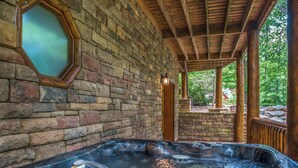 A hot tub area with a stone wall and wooden beams. - Pet Friendly Near Dollywood Cabin・Hot tub・Views (Sevierville)