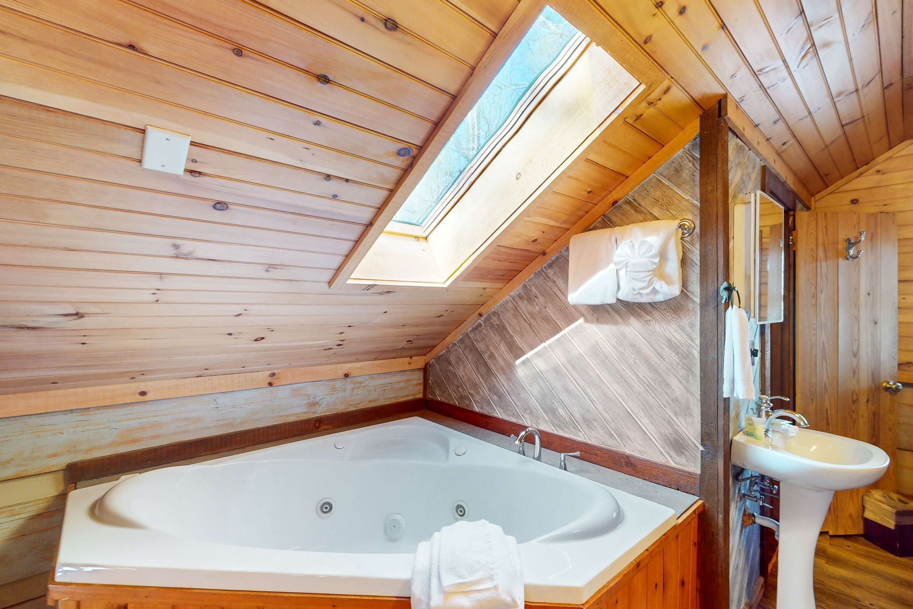 Ein Holzblock-Innenraum mit einer großen Badewanne, einem Waschbecken und einem Oberlicht.