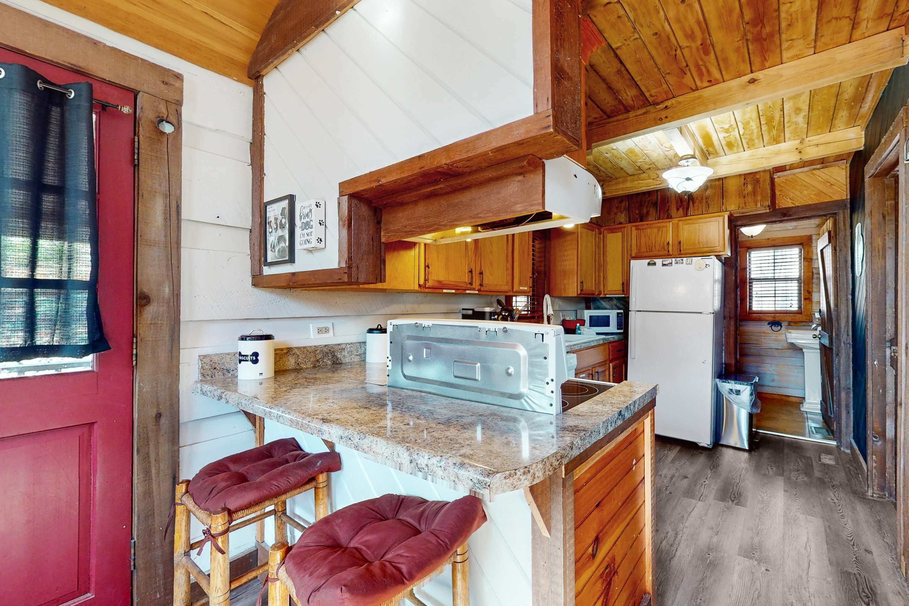 A kitchen with wooden cabinets, a granite countertop, a refrigerator, and a sink.