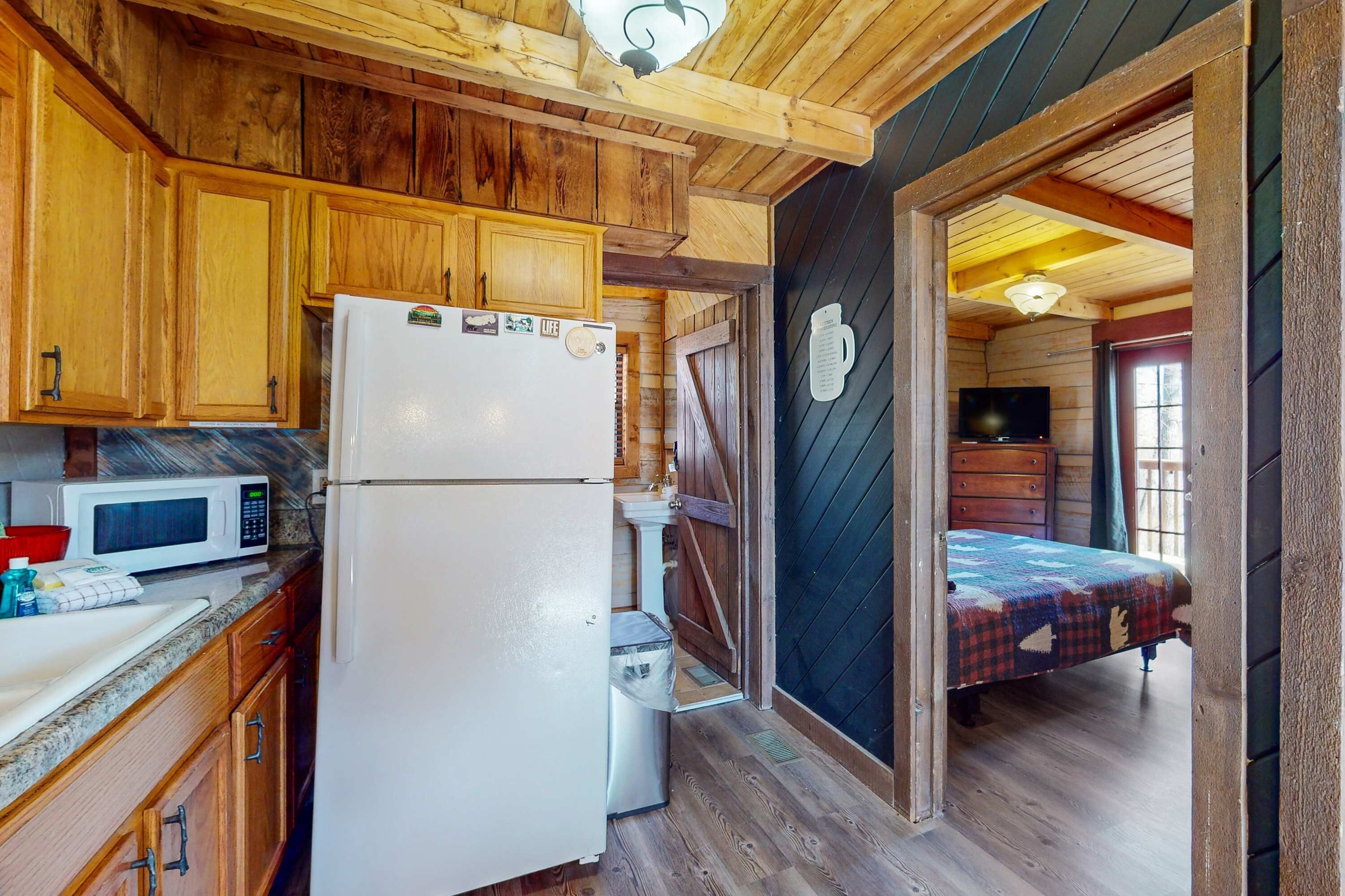 A compact kitchen with wooden cabinets, a refrigerator, and a microwave.