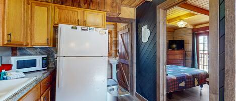 A compact kitchen with wooden cabinets, a refrigerator, and a microwave.