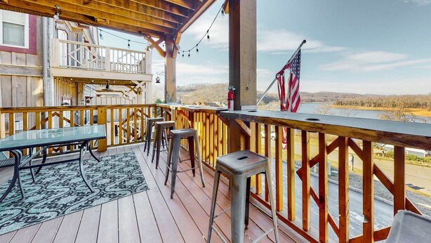 A wooden deck with a glass table and stools, overlooking a scenic landscape. - Spacious Norris Lake Retreat・View・Deck・BBQ Grill (Andersonville)