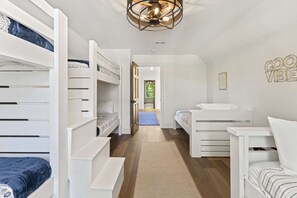 Ein Kinderzimmer mit Etagenbetten, einem kleinen Schreibtisch und einem Wandregal.