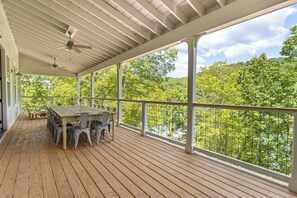 Eine überdachte Veranda mit Holzterrasse, einem Tisch und Stühlen sowie Blick auf eine bewaldete Landschaft.