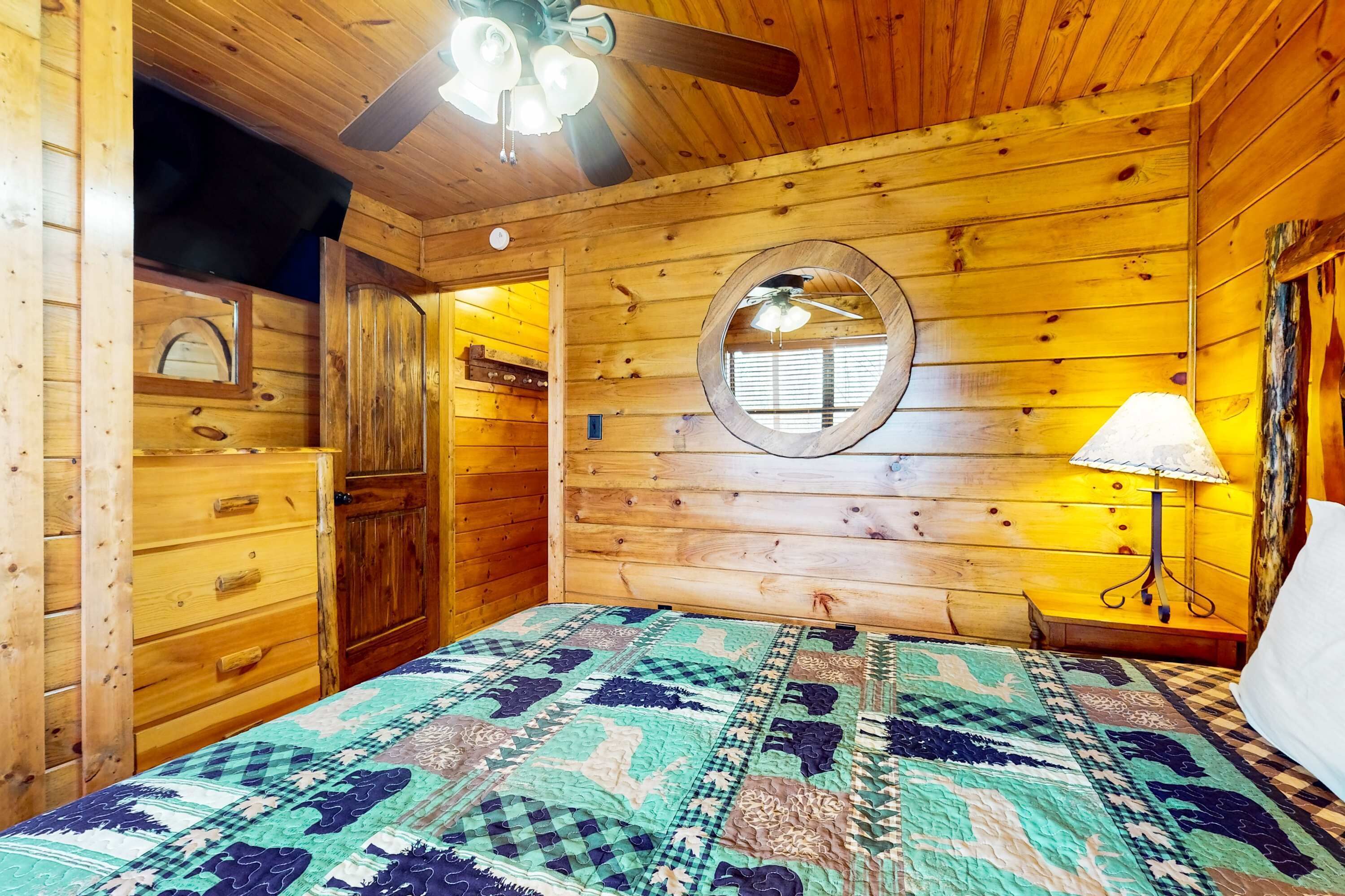 Een houten kamer met een bed, een plafondventilator, een spiegel en een lamp.