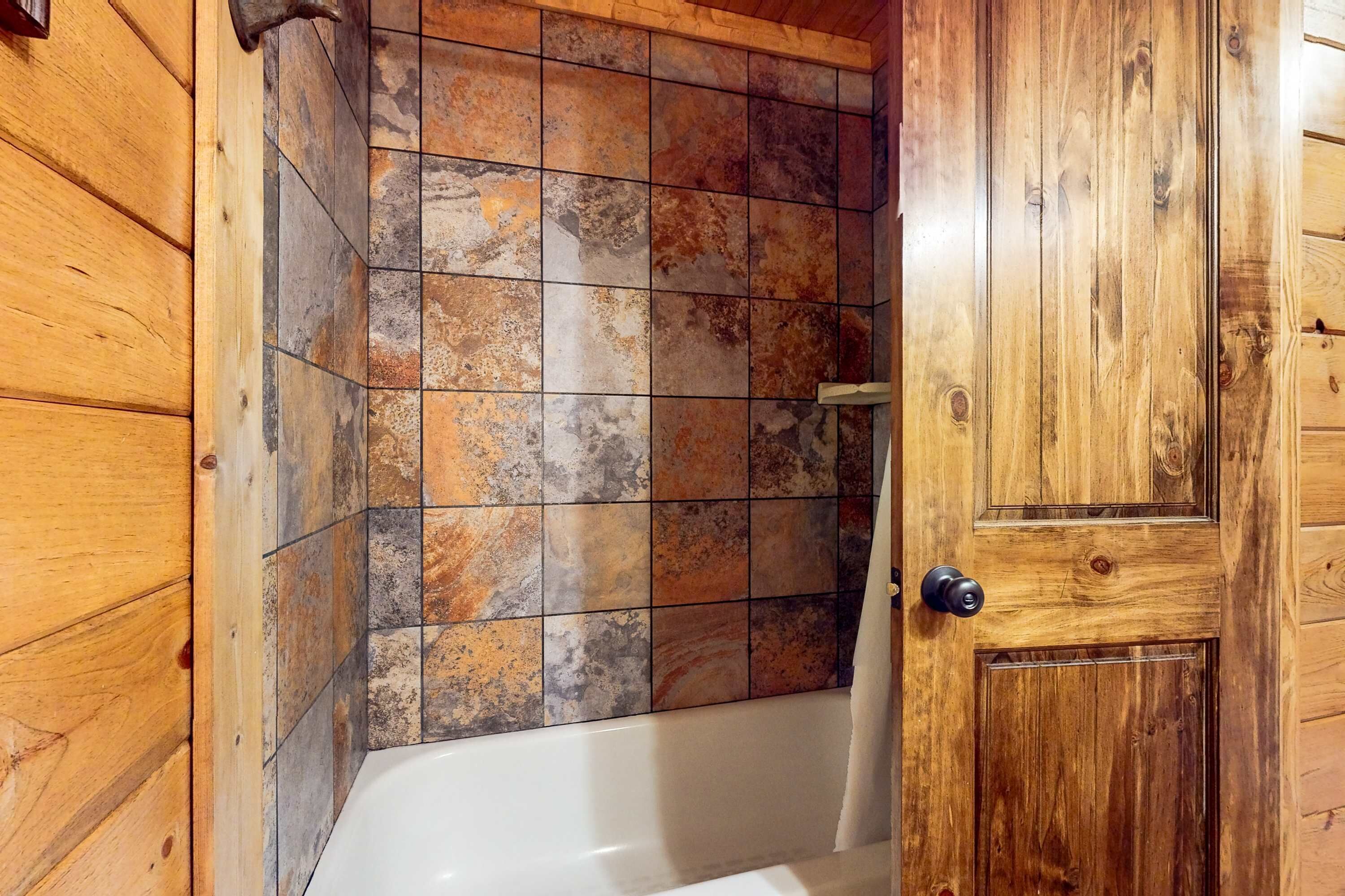 Ein Holzinnenraum mit einer Badewanne, gefliesten Wänden und einer Holztür.