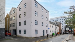 A multi-story building with a flat facade, several windows, and a parking area in front. - Benjamin Suite Modern 3BR Apartment (Cardiff)