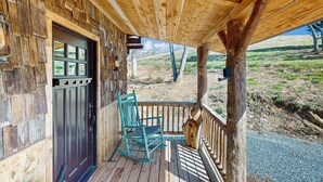 A wooden porch with a rocking chair and a door leading to a room. - Cozy Lake Front Cabin, Sleeps 4, Dock, Play Yard (Dandridge)