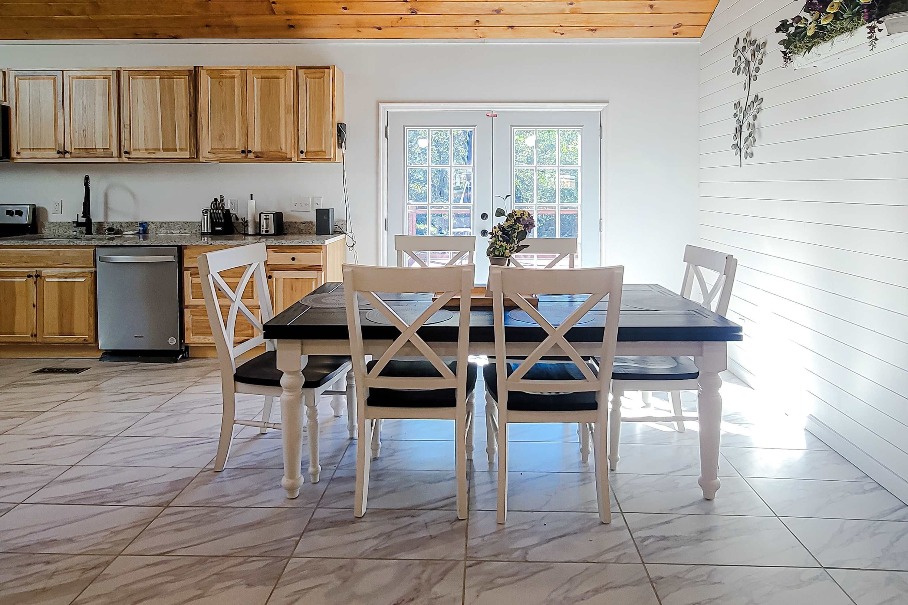Una cocina con armarios de madera, lavavajillas y una mesa de comedor con sillas.