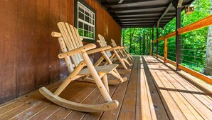 Eine Holzveranda mit Schaukelstühlen und Deckenventilator.