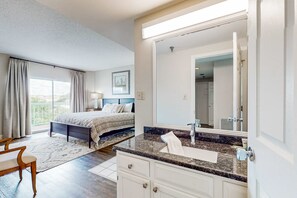 A bedroom with a bed, a bathroom with a sink and mirror, and a balcony with curtains. - Top-Floor River & Mtn View Condo・Sleeps 6・Pool (Pigeon Forge)