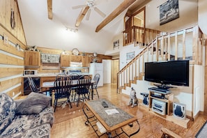A cozy cabin interior with a dining area, kitchen, and a living room featuring a TV and speakers. - Casual Cabin, Sleeps 6, Hot Tub, Grill, Fireplace (Pigeon Forge)