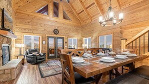 A spacious wooden dining area with a long table set for a meal, flanked by wooden chairs. - Spacious Cabin, Sleep 22, Hot Tub, Game, Theatre, View (Pigeon Forge)
