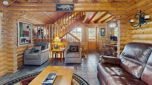 A log cabin interior with a wooden staircase, leather sofa, and rustic decor. - Quiet Gatlinburg Retreat・Hot tub・Fireplace・Pool (Gatlinburg)