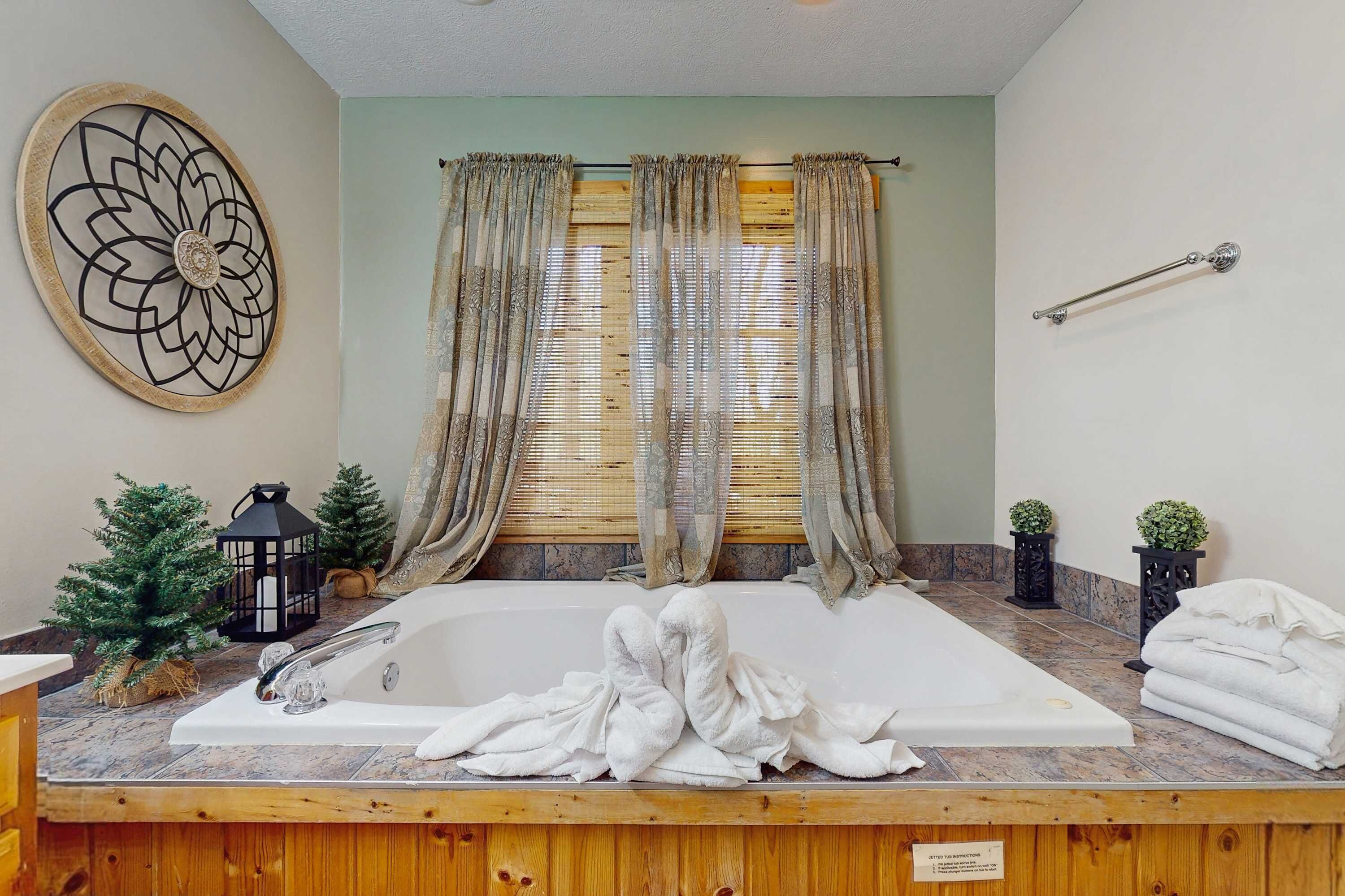 A bathroom with a large bathtub, wooden paneling, a decorative wall piece, and a towel rack.