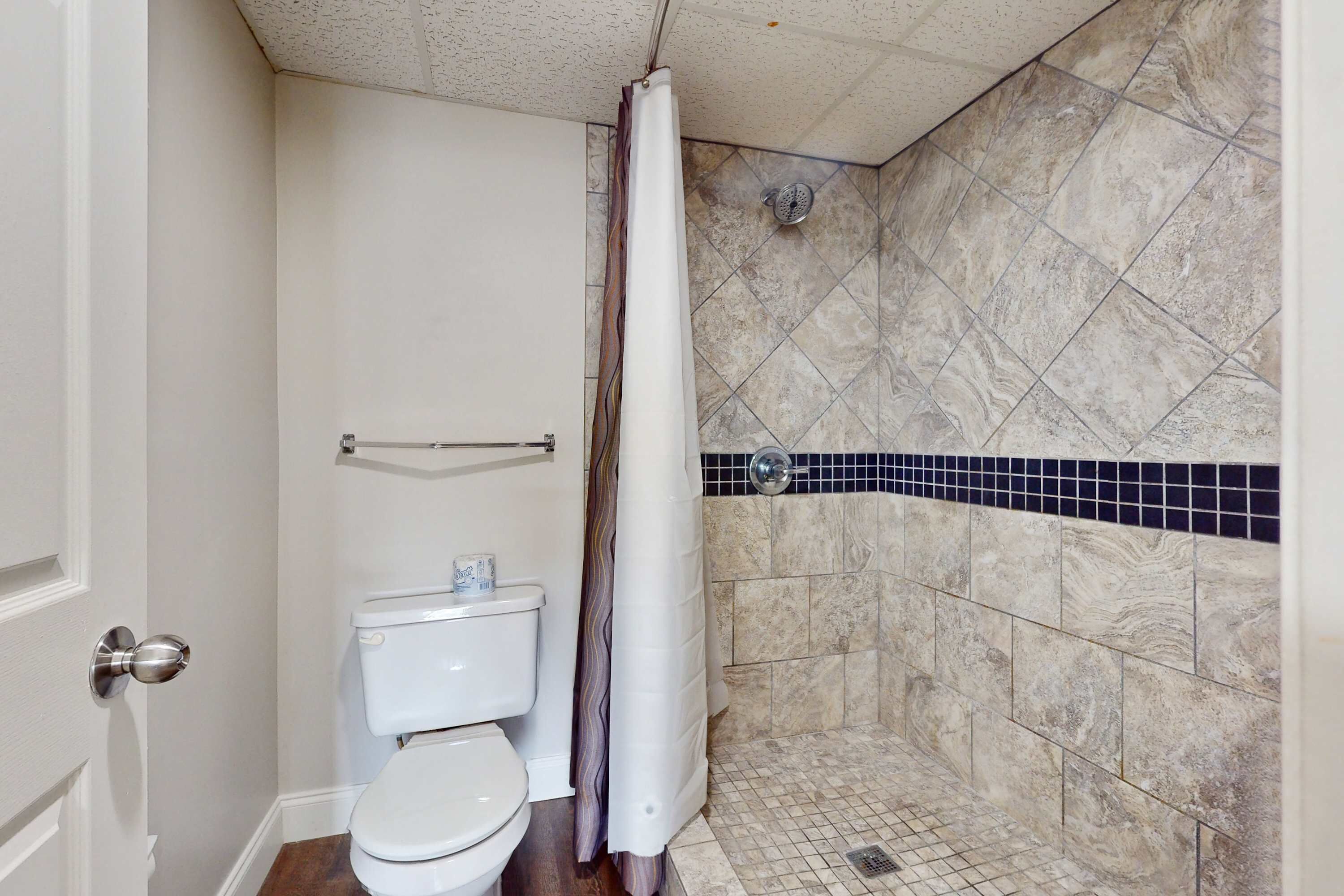 A bathroom with a toilet, shower, and tiled walls.