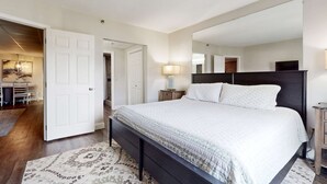 A bedroom with a bed, a nightstand, a mirror, and a door leading to another room. - Dual-Suite Riverside Condo, Sleeps 4, Views, Pool (Pigeon Forge)