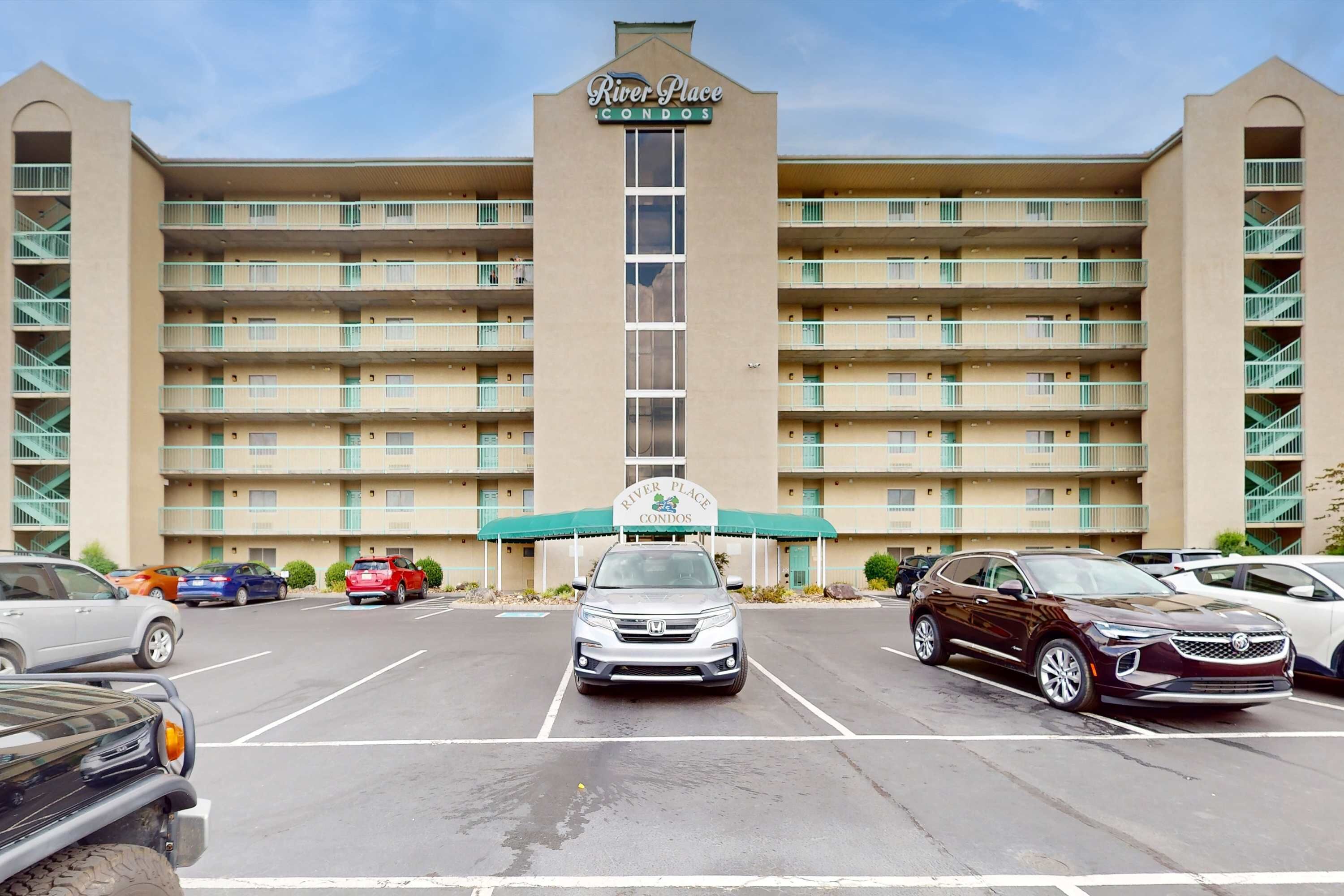 A multi-story hotel with a central entrance and a sign reading "River Place Condos".
