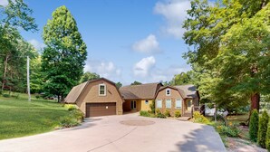 Une maison à deux étages avec une allée menant à l’entrée, un garage et une pelouse bien entretenue.