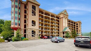Ein mehrstöckiges Hotel mit Innenhof, Balkonen und Parkplatz.