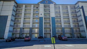 A multi-story building with a prominent number '5' on the facade, multiple balconies, and a parking area in the foreground. - Mtn View Getaway, Sleeps 6, Bunk nook, Shared Pool (Pigeon Forge)