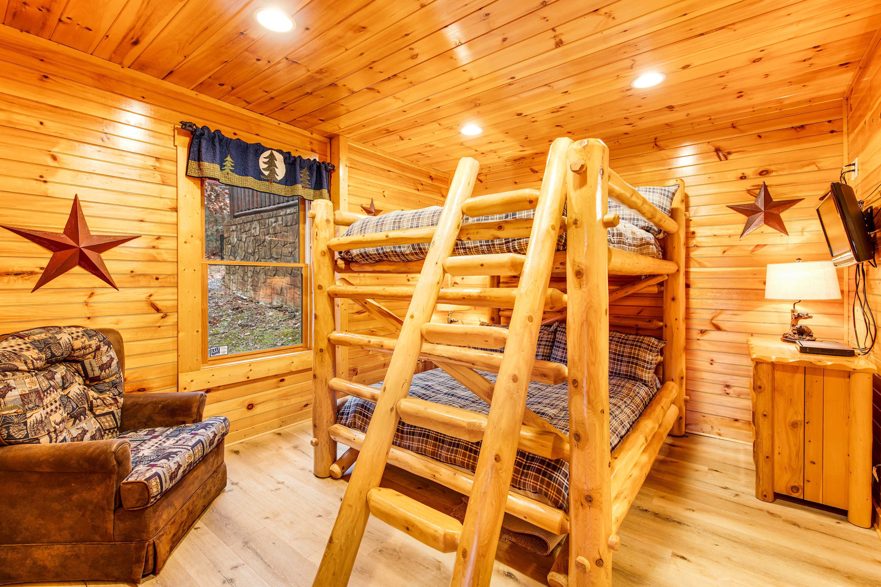 Una cabaña acogedora con una litera, una escalera de madera, un sillón estampado de cuadros y una decoración de estrella en la pared.