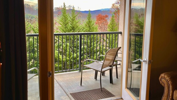 A balcony with a view of trees and mountains, a chair, and a door. - 2.4 Mi. to DT Pigeon Forge Stay・Hot Tub・Grill・Pool (Pigeon Forge)