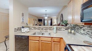 A modern kitchen with wooden cabinets, a dishwasher, a double sink, and a microwave. - 2.4 Mi. to DT Pigeon Forge Stay・Hot Tub・Grill・Pool (Pigeon Forge)