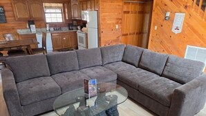 Ein modernes Wohnzimmer mit Ecksofa, Glastisch und Holzboden.