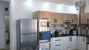 Une cuisine moderne dotée d’appareils électroménagers en acier inoxydable, de meubles en bois et d’une table à manger en verre.