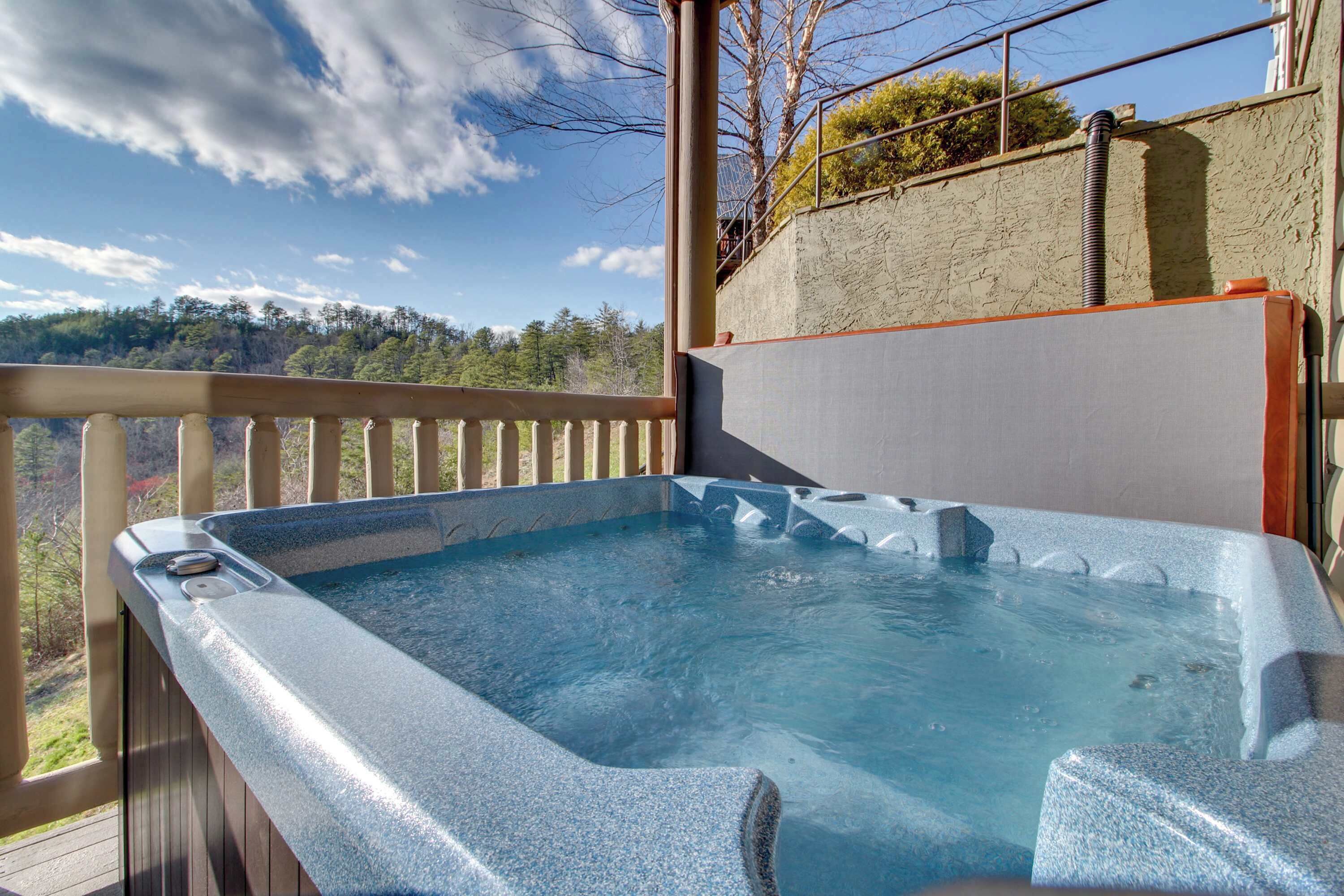 Un jacuzzi en una terraza de madera con vistas a un paisaje boscoso.
