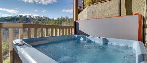 Un jacuzzi en una terraza de madera con vistas a un paisaje boscoso.