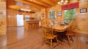 L’intérieur d’un chalet en bois comprend une cuisine, un coin repas et une grande fenêtre.