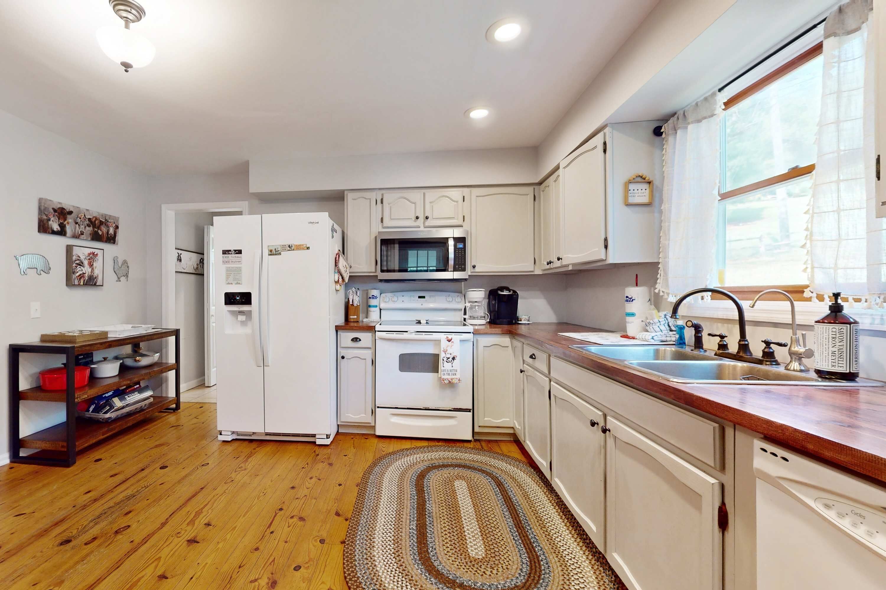 A compact kitchen with white cabinets, a microwave, a stove, and a sink.