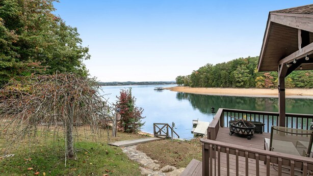 Une terrasse au bord du lac offrant une vue sur celui-ci, un espace salon abrité et un sentier en pierre menant à l’eau.