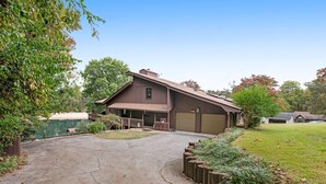 Une maison à deux étages avec un garage, un porche à l’avant et une allée menant au garage.
