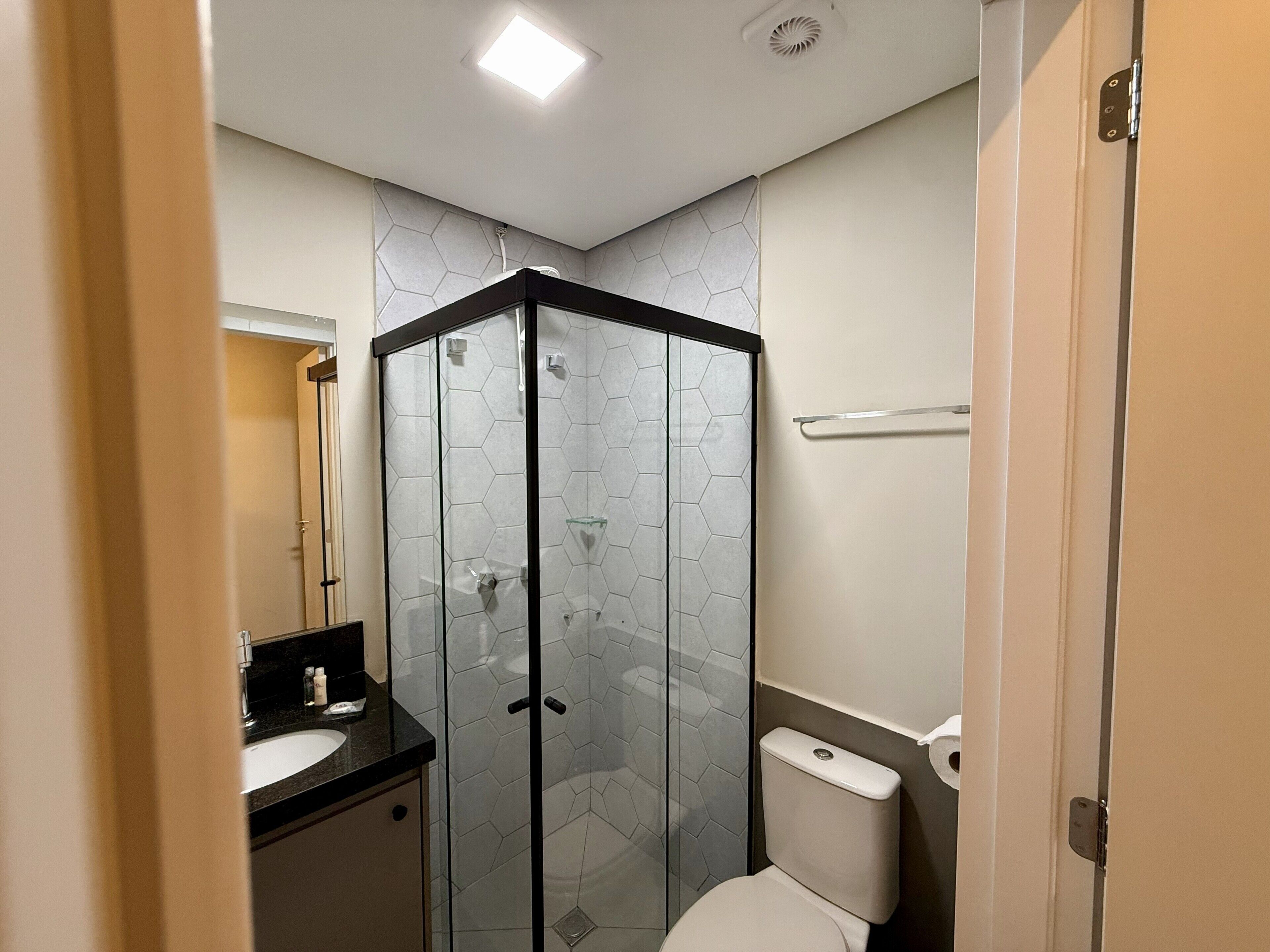 Ein Badezimmer mit Duschkabine, Toilette, Waschbecken und Spiegel.