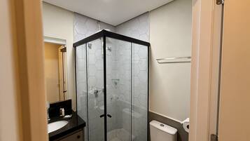 Ein Badezimmer mit Duschkabine, Toilette, Waschbecken und Spiegel.