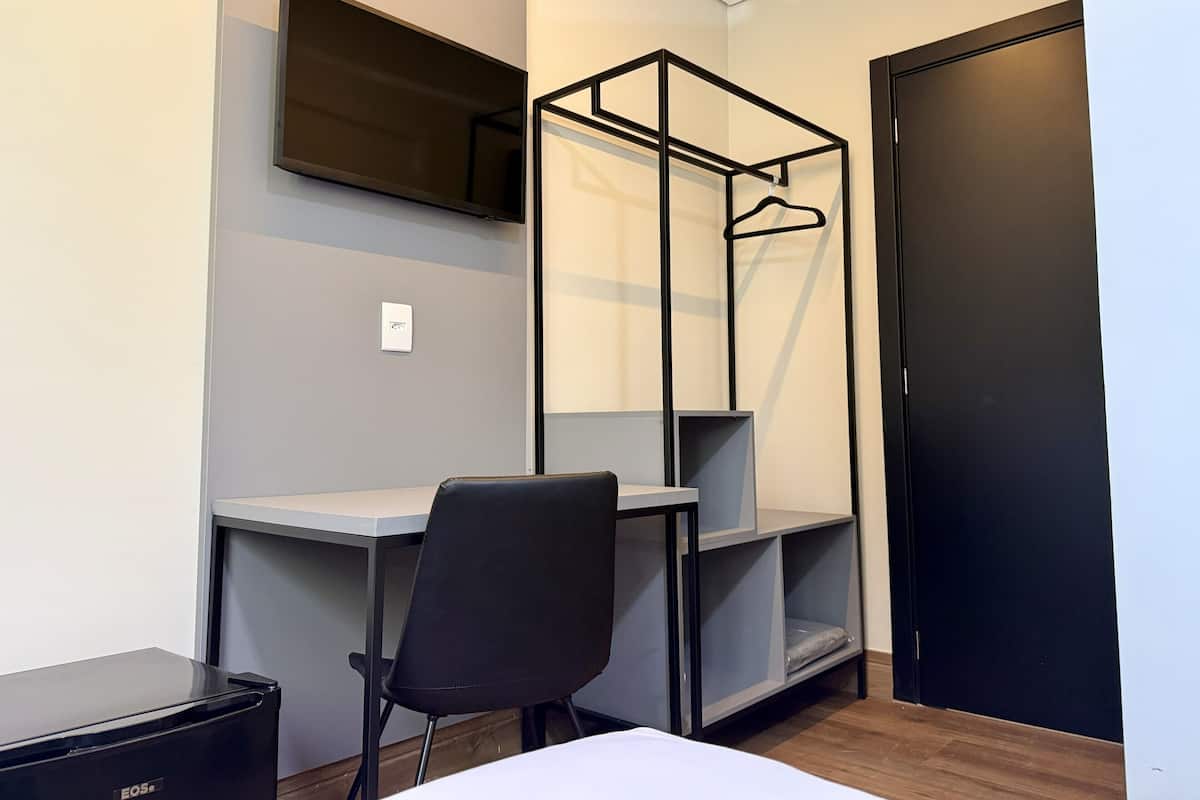 A compact room with a desk, chair, and built-in shelving unit.
