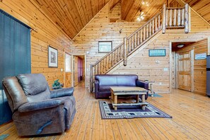 A cabin interior with a wooden interior, a leather recliner, a blue sofa, a wooden coffee table, and a staircase. - 5.5 Mi to DT Pigeon Forge・Serene Getaway・Hot Tub (Sevierville)