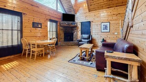 Ein gemütliches Blockhaus-Interieur mit Essbereich, Kamin, einer Ledersofa und einem Fernseher.