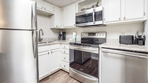 A compact kitchen with white cabinets, a stainless steel refrigerator, a microwave, an oven, and a toaster. - 2 All-Suite Condos, Sleeps & River View Balconies (Pigeon Forge)