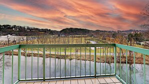 A balcony with a view of a river and distant hills. - 2 All-Suite Condos, Sleeps & River View Balconies (Pigeon Forge)