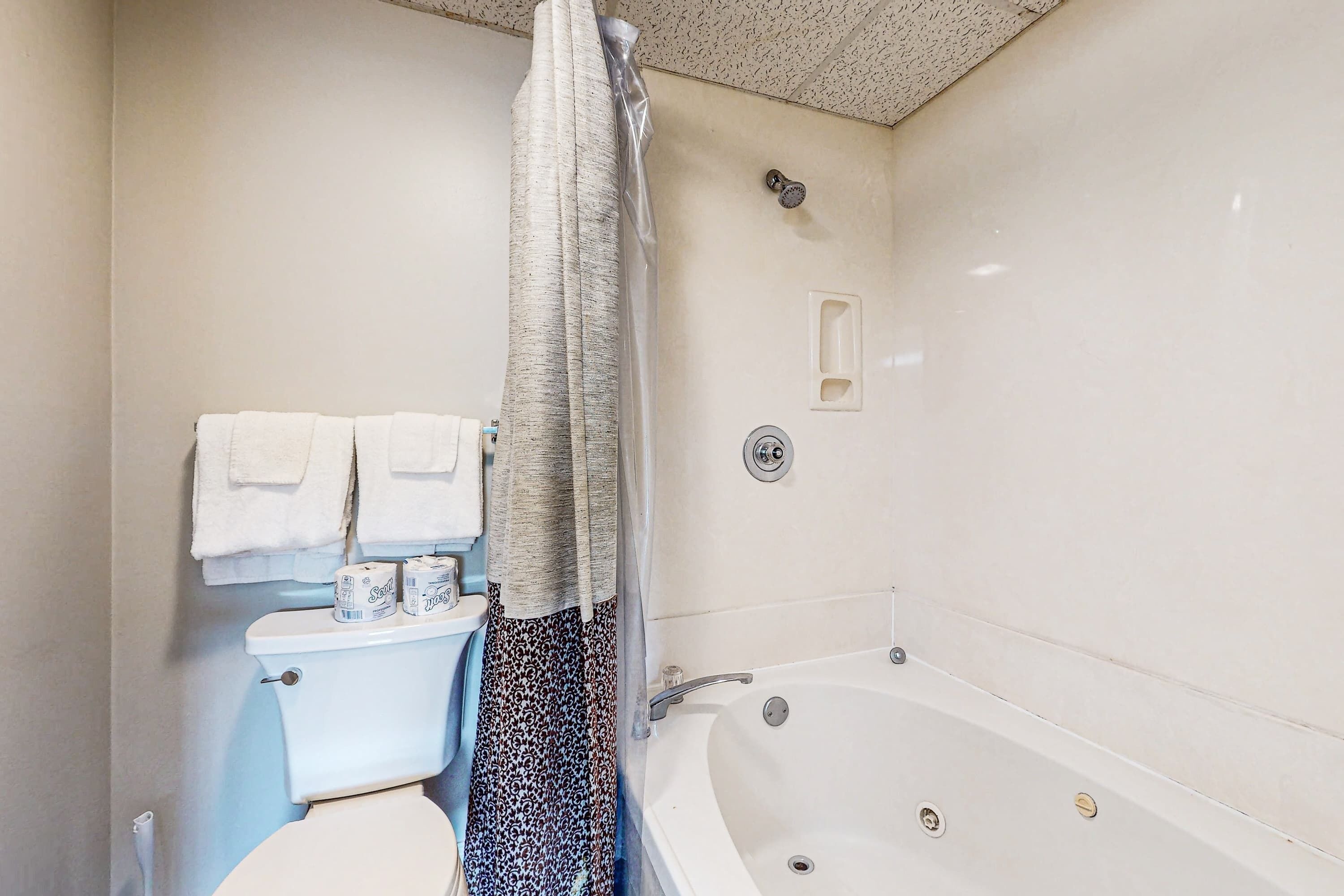 Un baño con inodoro, ducha con cortina y bañera.