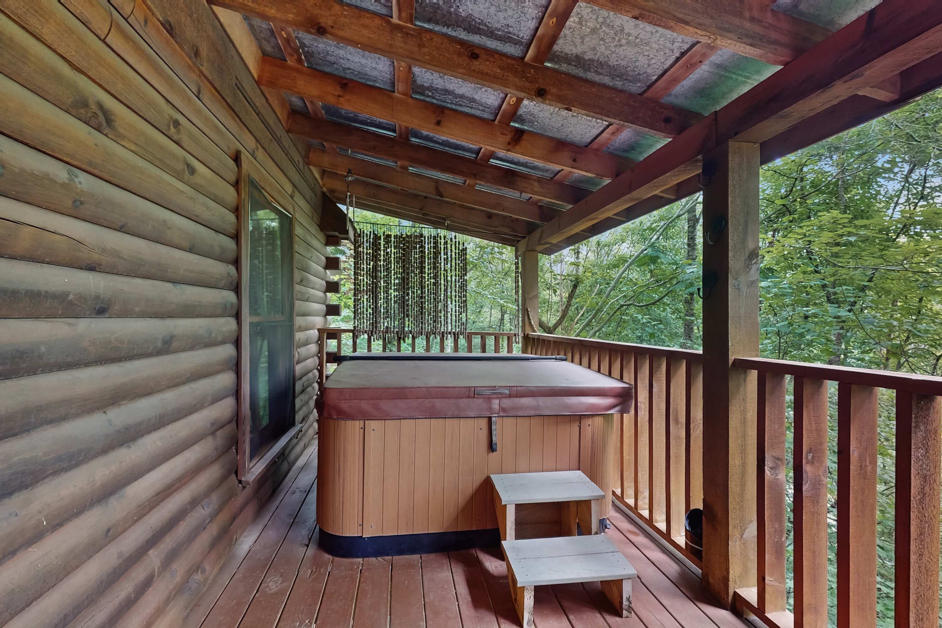Une cabane en bois avec un jacuzzi, une terrasse en bois et une vue sur la forêt.