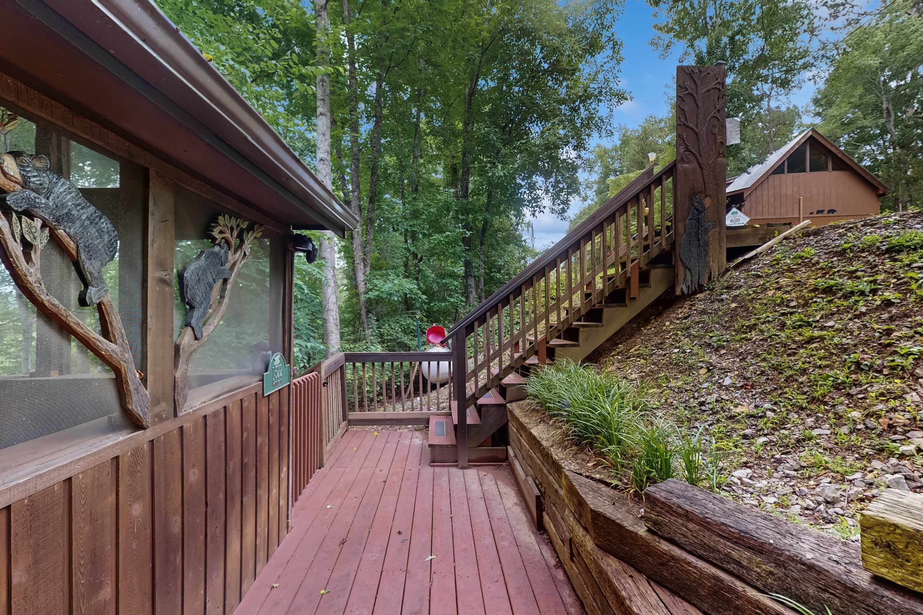 Une terrasse en bois avec une rambarde, entourée d’arbres.
