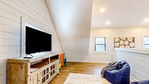 A room with a wooden entertainment unit, a television, a bean bag, and a rug. - Brand New Cabin Overlooking Douglas Lake・Hot Tub (Sevierville)