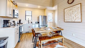 A modern kitchen with white cabinetry, stainless steel appliances, and a wooden dining table with leather chairs. - Brand New Cabin Overlooking Douglas Lake・Hot Tub (Sevierville)