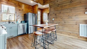 Een moderne keuken met houten wanden, roestvrijstalen apparatuur en een bar met krukken.