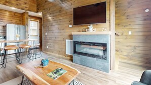 Een moderne keuken met houten wanden, een grote flatscreen televisie en een ingebouwde open haard.
